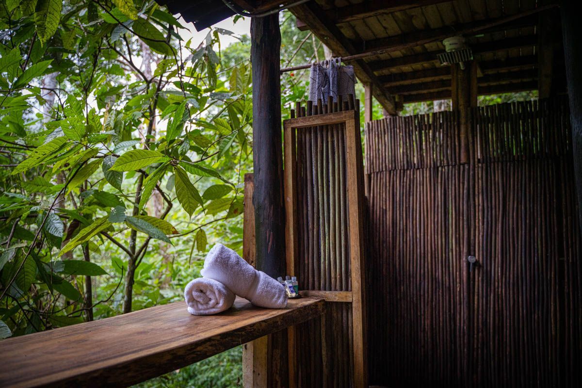 Two towels are sitting on a wooden table in front of a wooden shower.