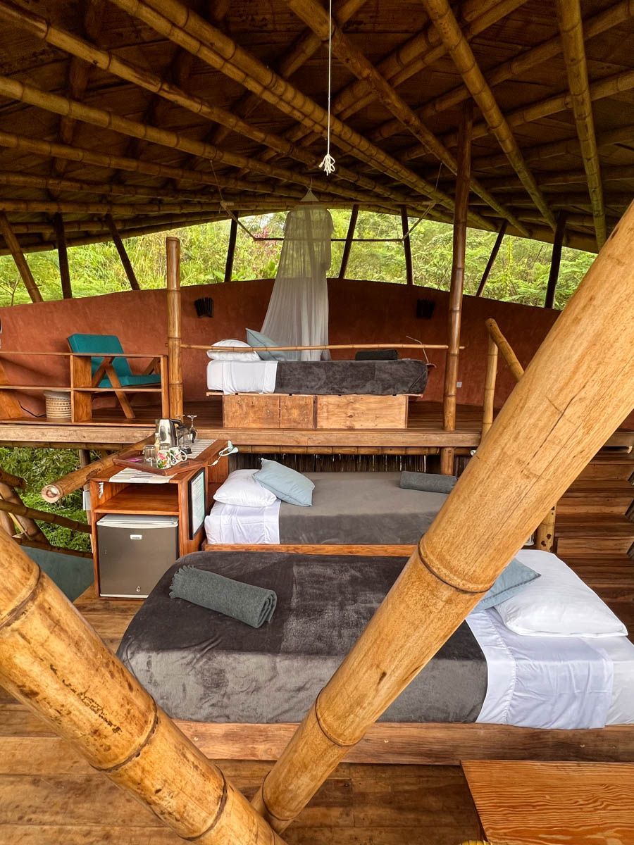 A room with three beds and a roof made of bamboo.