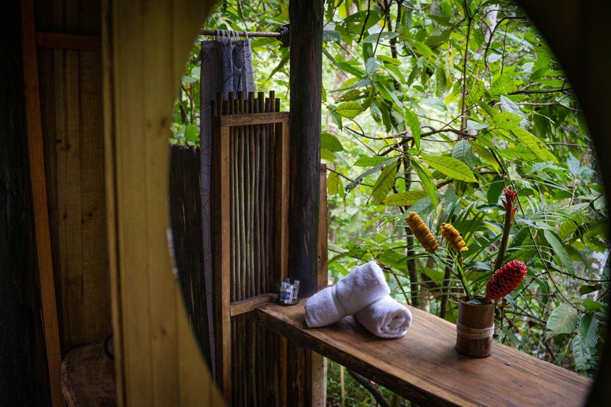 A wooden table with towels and flowers on it in front of a mirror.