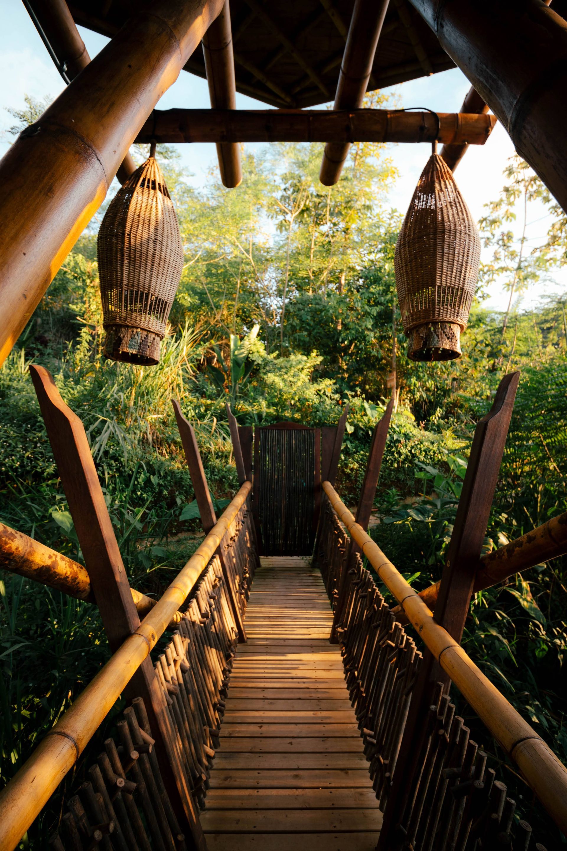A wooden bridge leading to a house in the woods.