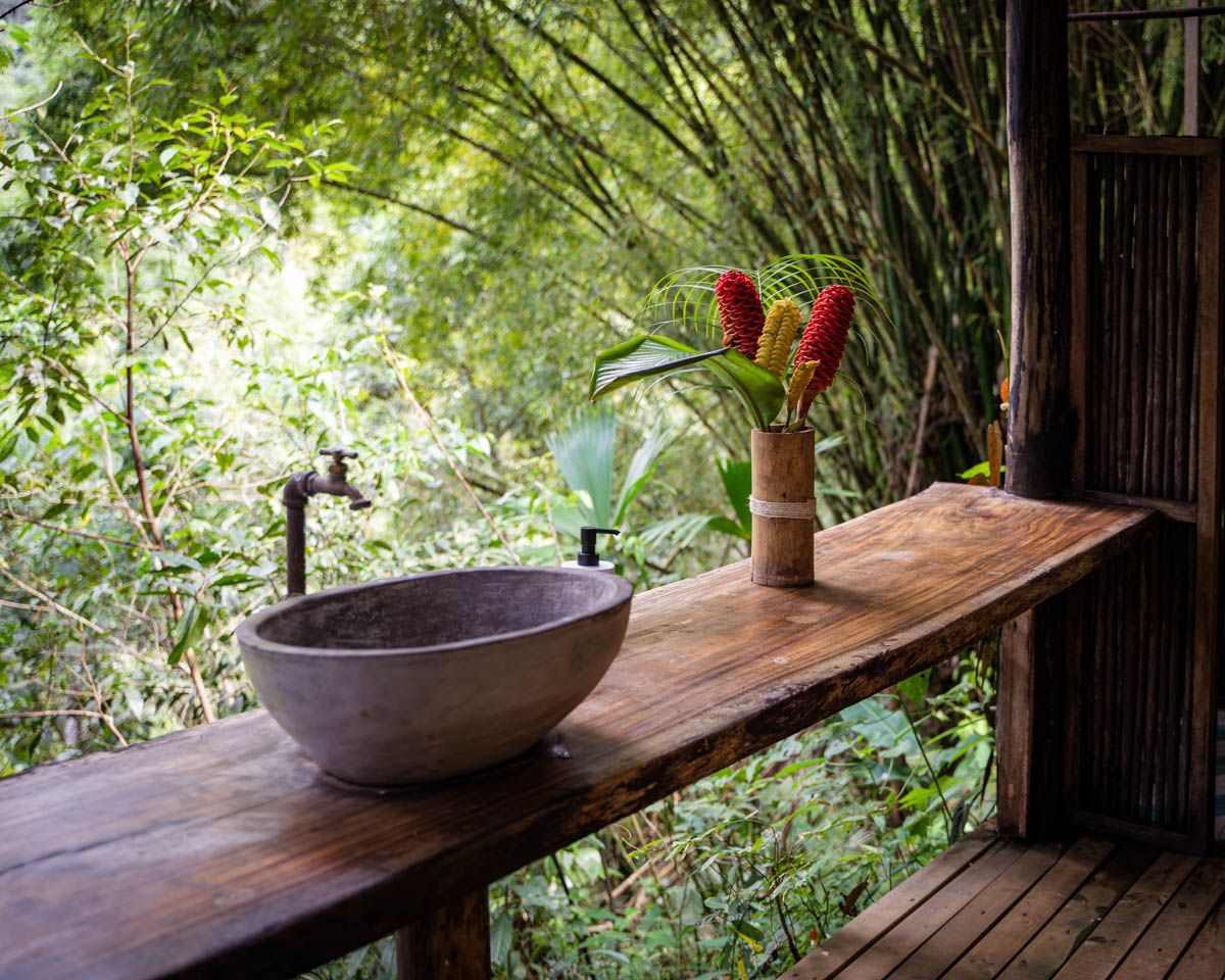 A wooden table with a sink and a vase of flowers on it.