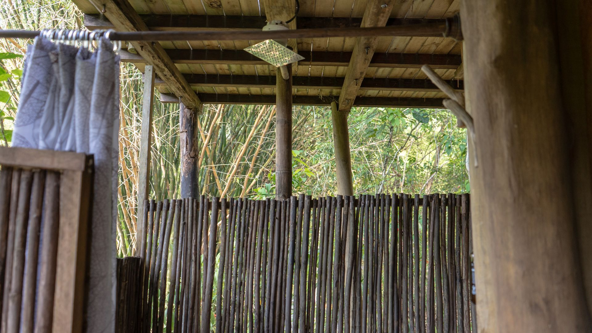 A wooden shower stall with a curtain hanging from the ceiling.