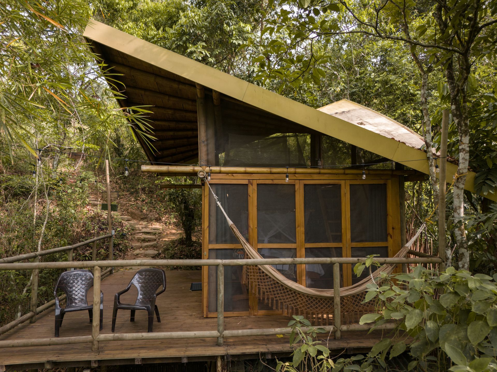 A small house with a hammock and chairs on the deck.