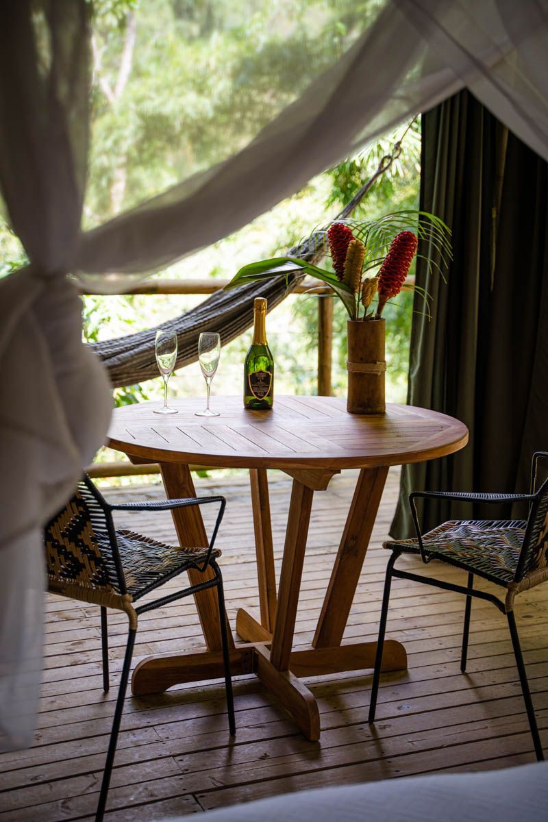 A wooden table with a vase of flowers and a bottle of wine on it.