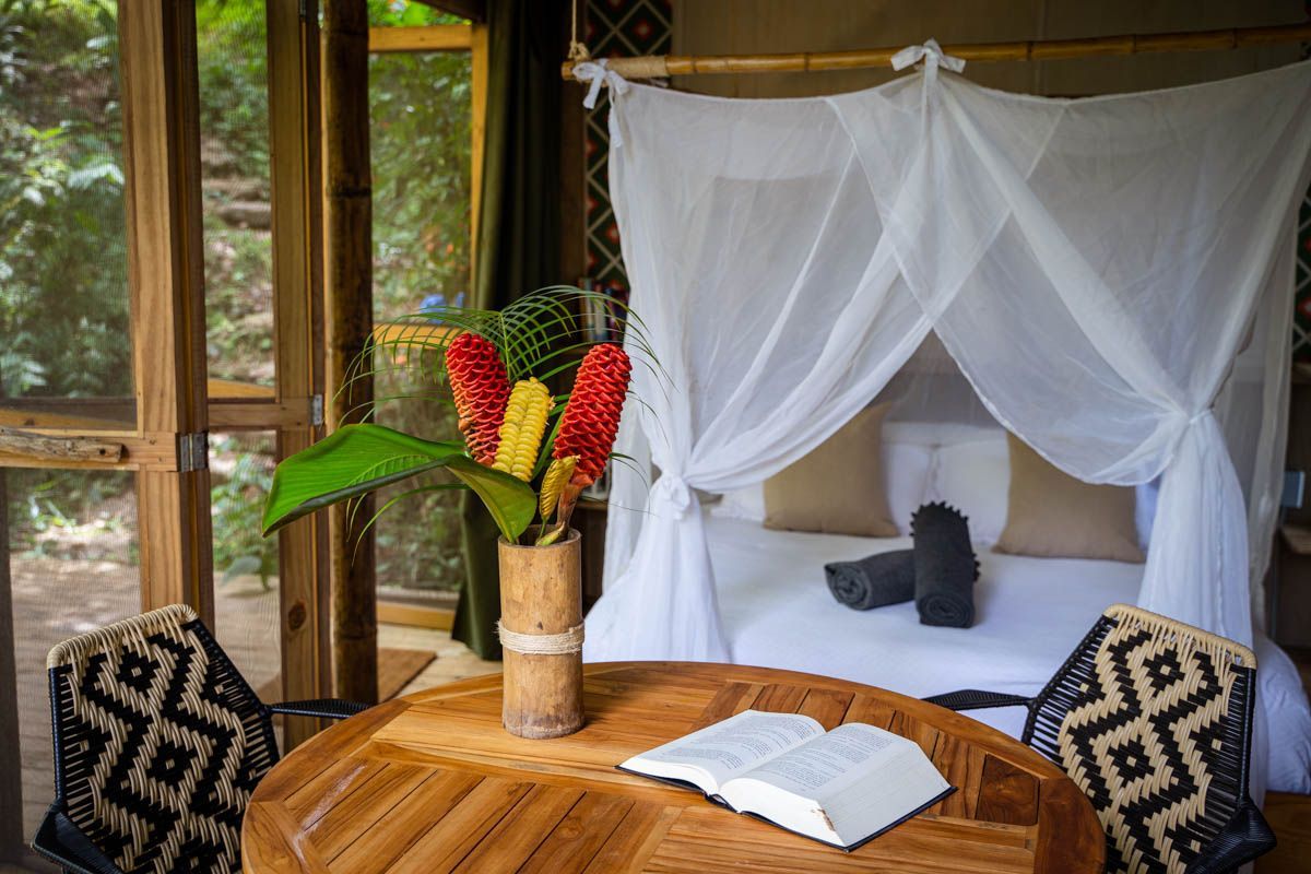 There is a table with a book on it in front of a canopy bed.