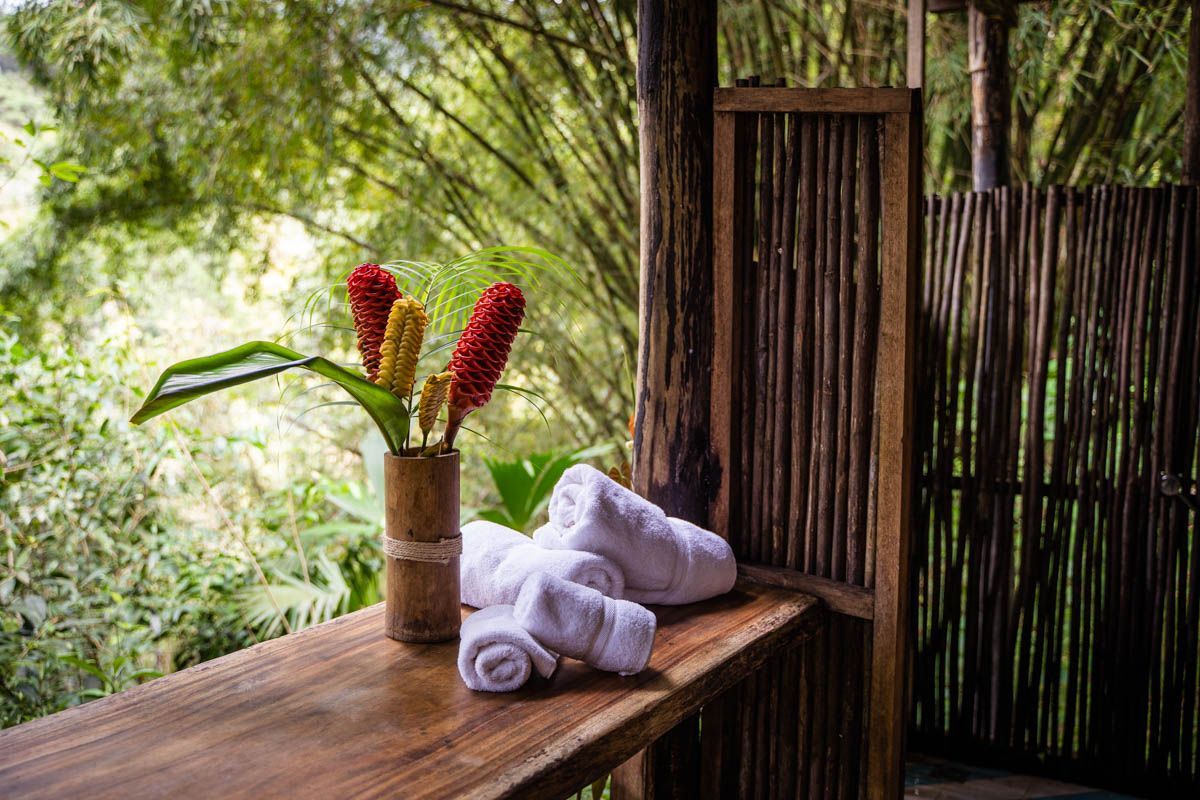 A wooden table with a vase of flowers and towels on it.