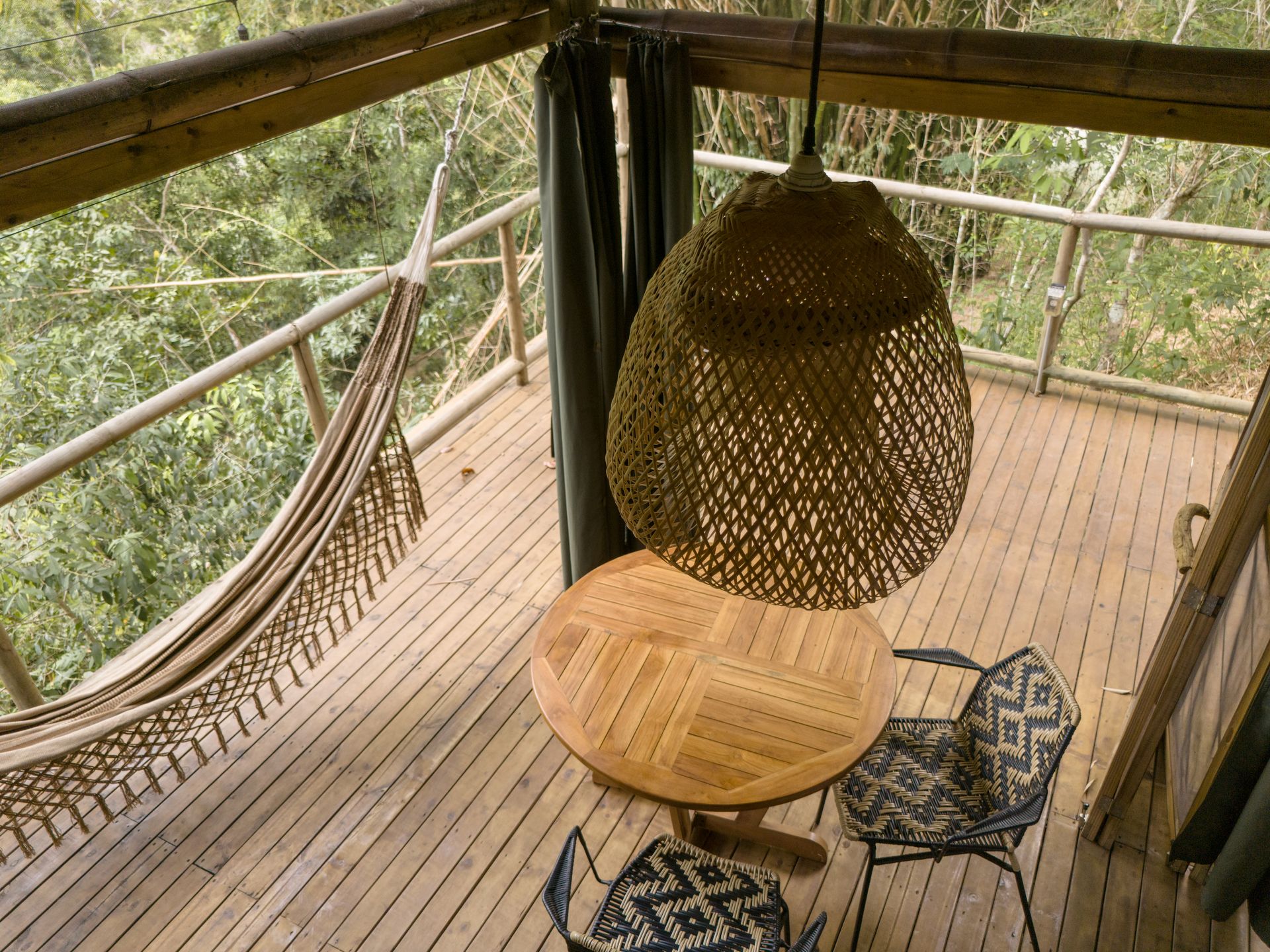 A wooden deck with a table and chairs and a hammock.