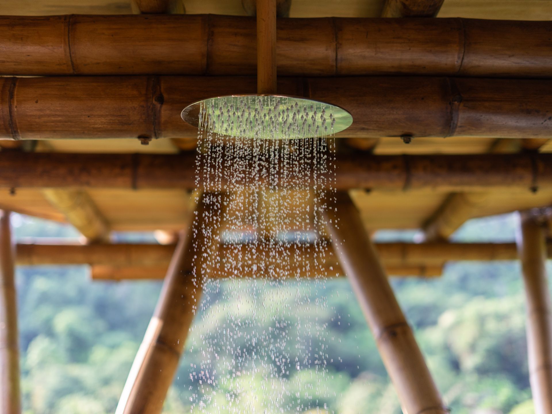 A shower head is hanging from the ceiling of a bamboo structure.