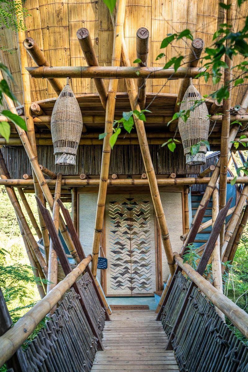 A wooden bridge leading to a bamboo house.