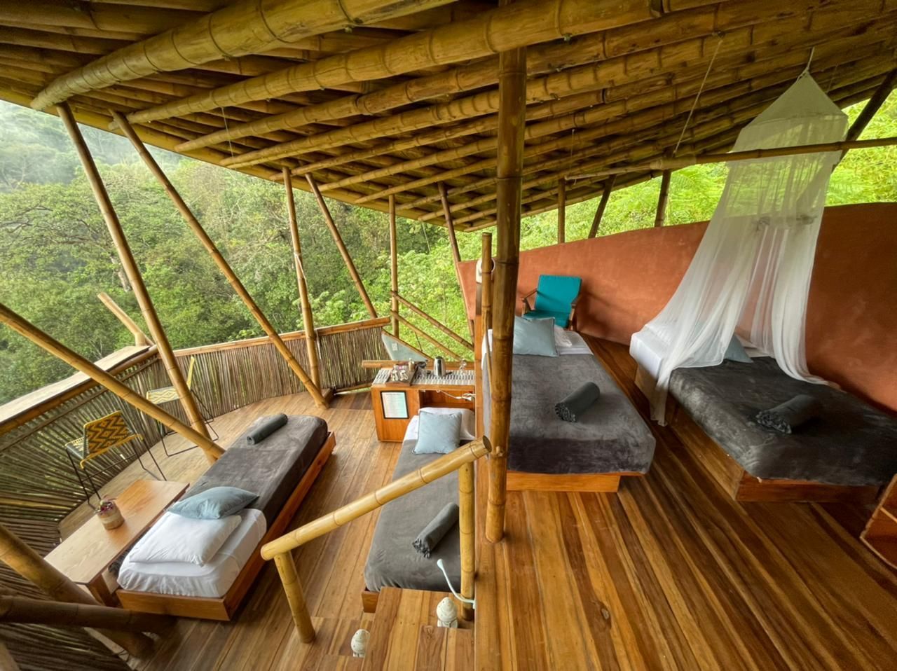A room with two beds and a mosquito net on the ceiling.