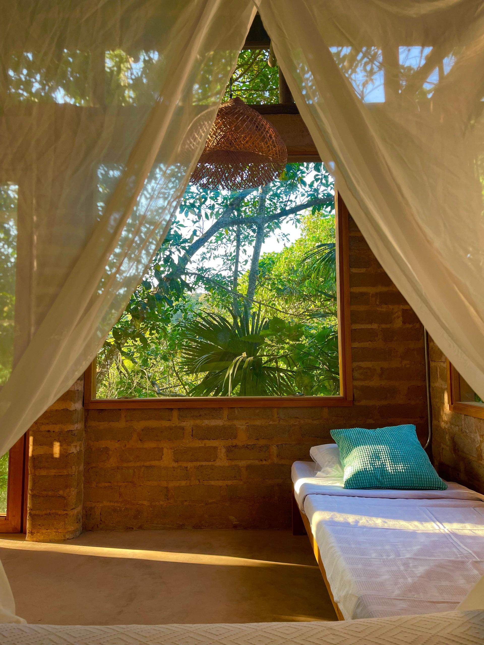A bedroom with a canopy bed and a window with trees in the background