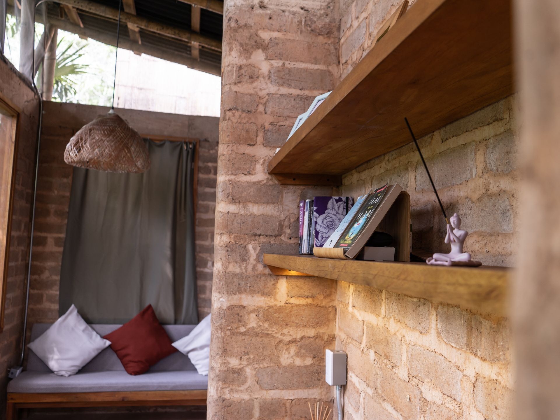 A brick wall with a wooden shelf with books on it