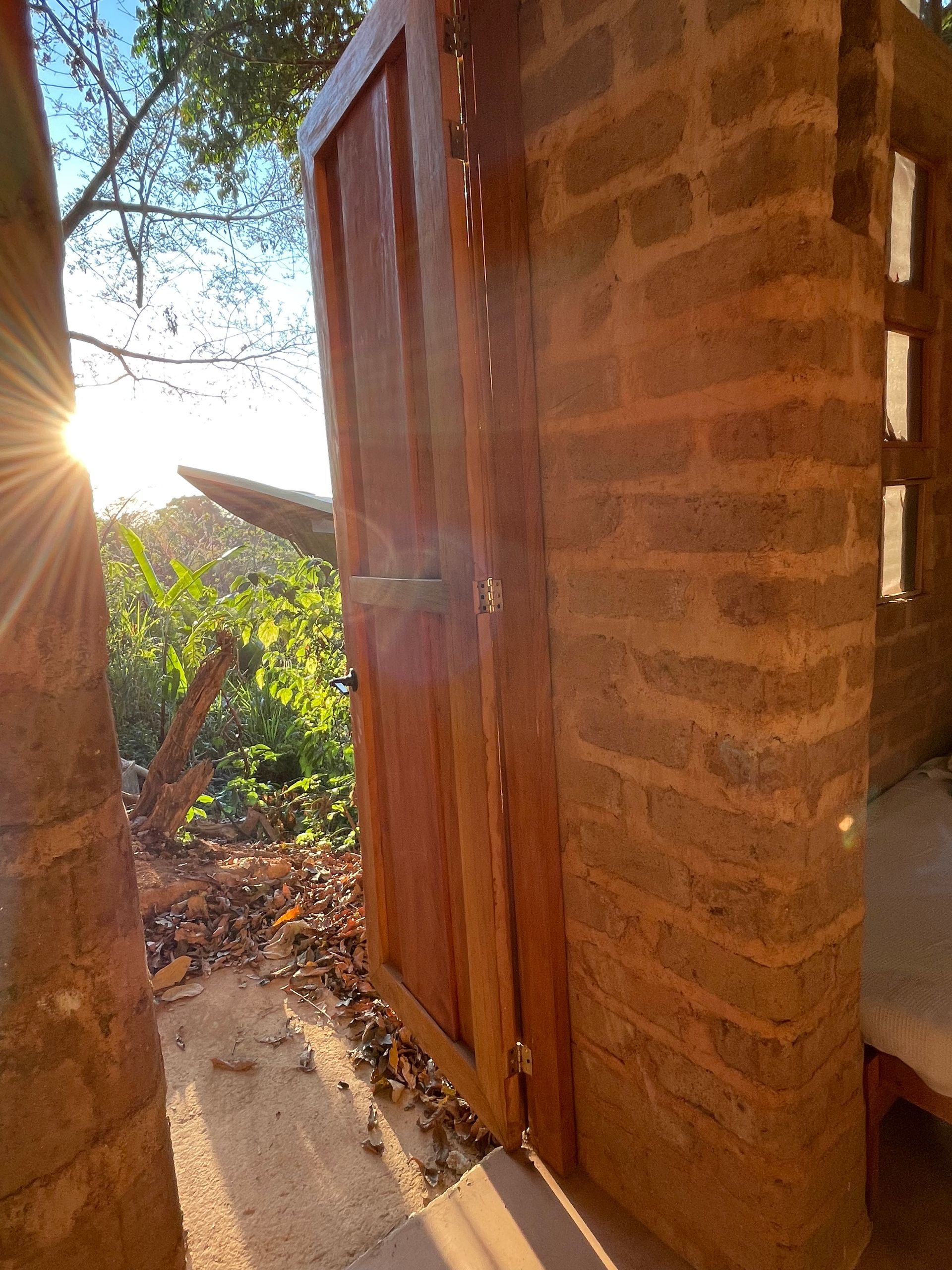 The sun is shining through a wooden door in a brick building.