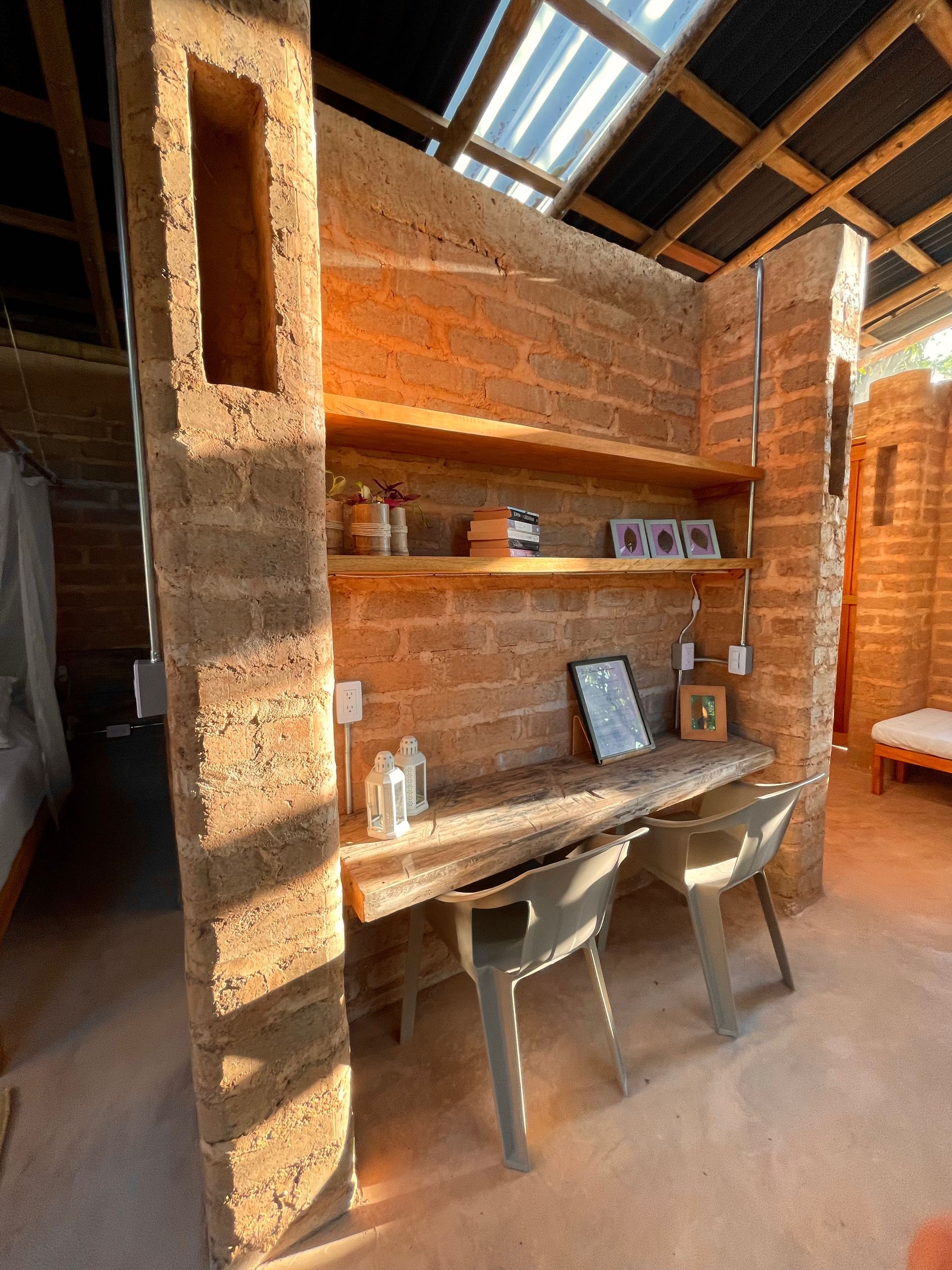 A room with a brick wall and a desk and chairs