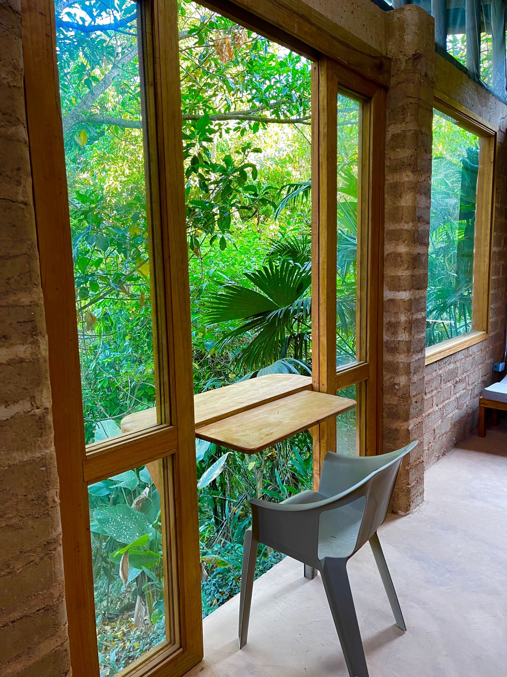 A chair is sitting in front of a window with a view of a forest.