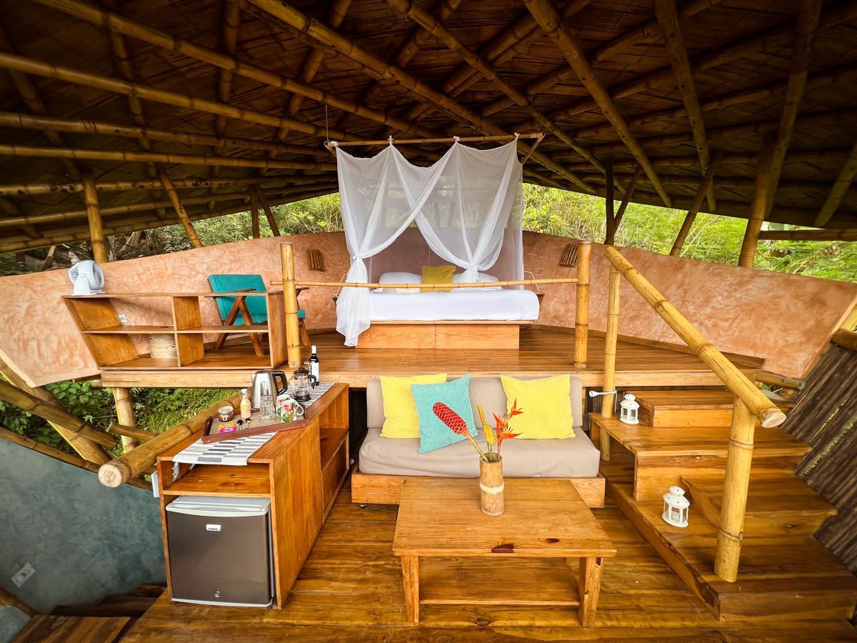 A wooden house with a bed , couch , table and refrigerator.