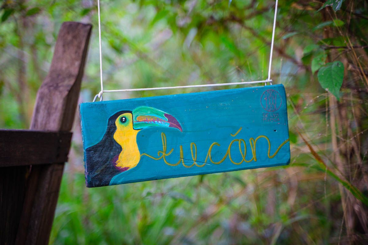 A blue sign with a toucan on it is hanging from a rope.