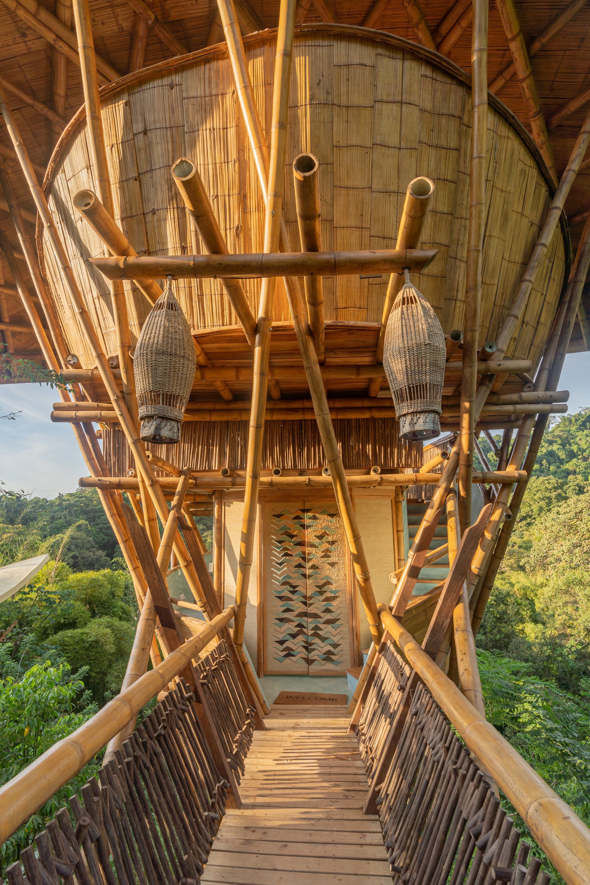 A wooden bridge leading to a bamboo house in the woods.