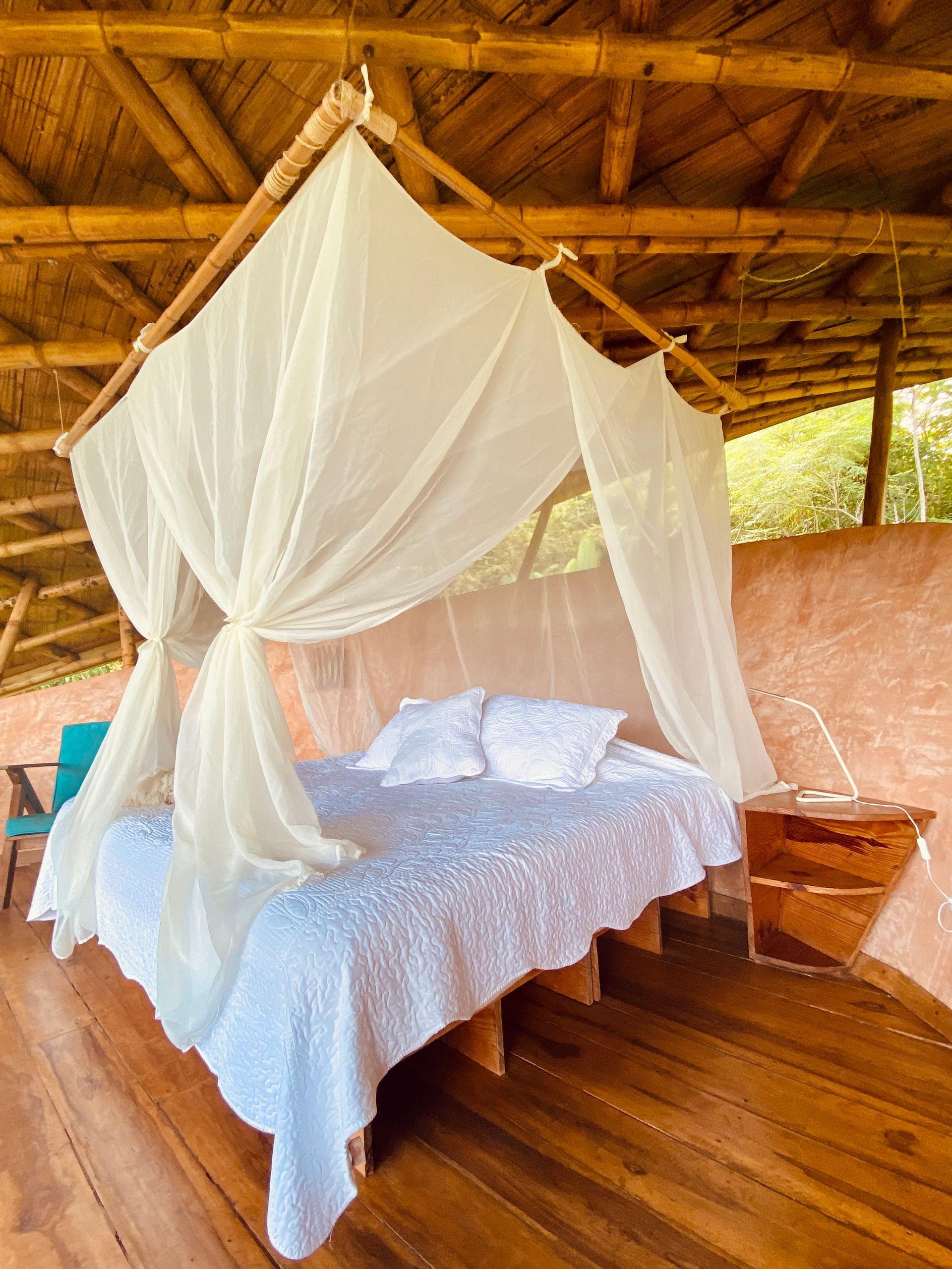 A bed with a canopy over it is sitting on a wooden floor.