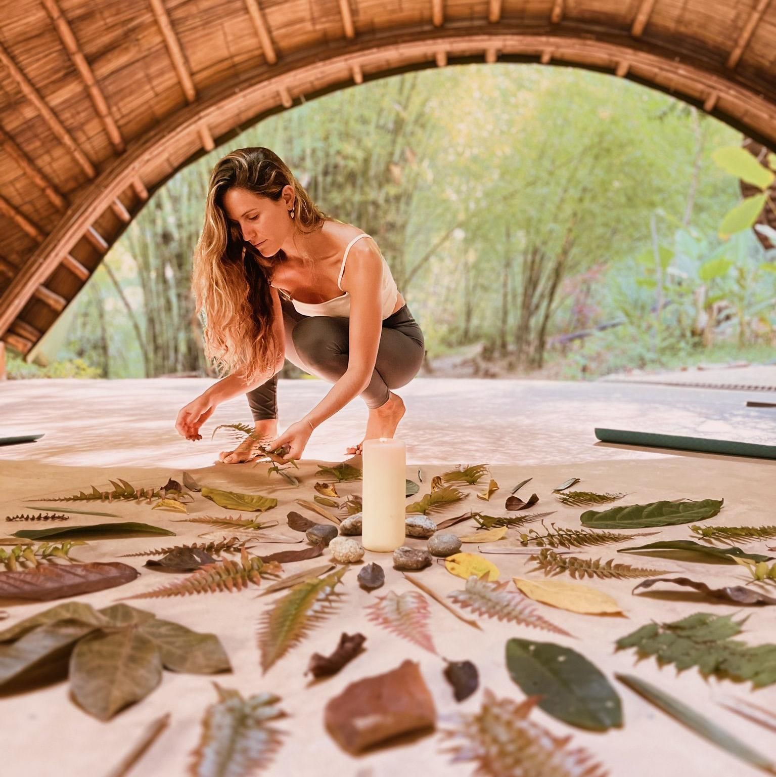 A woman is kneeling on a table with leaves and a candle.