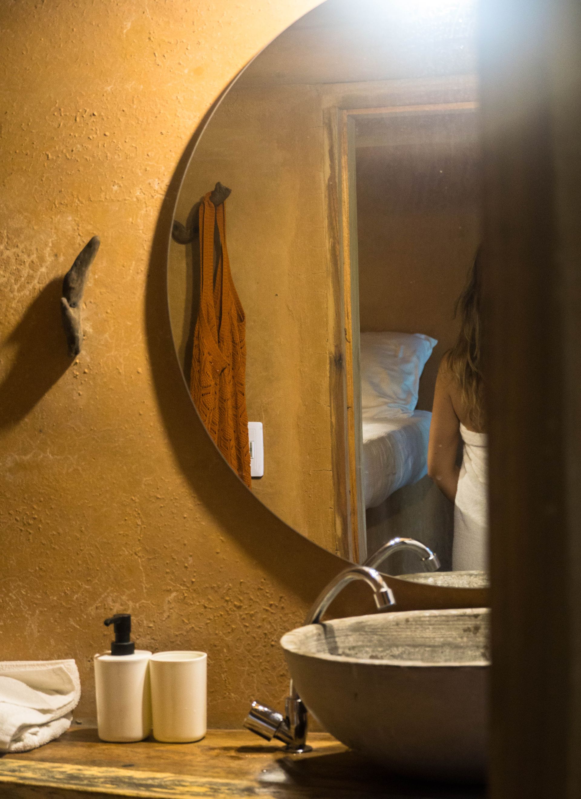 A woman is standing in front of a bathroom sink and mirror.
