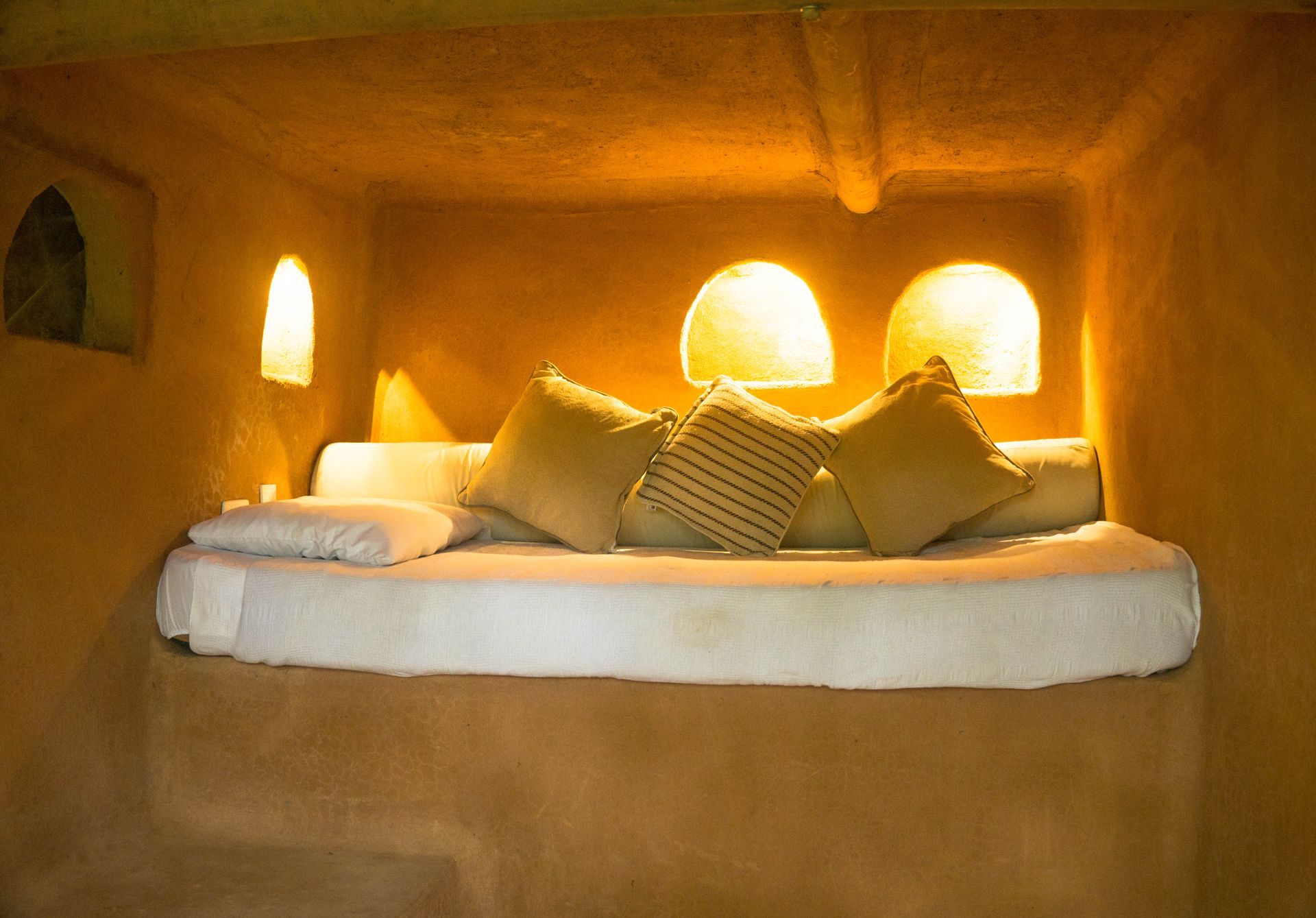 A bed with a mattress and pillows in a corner of a room.