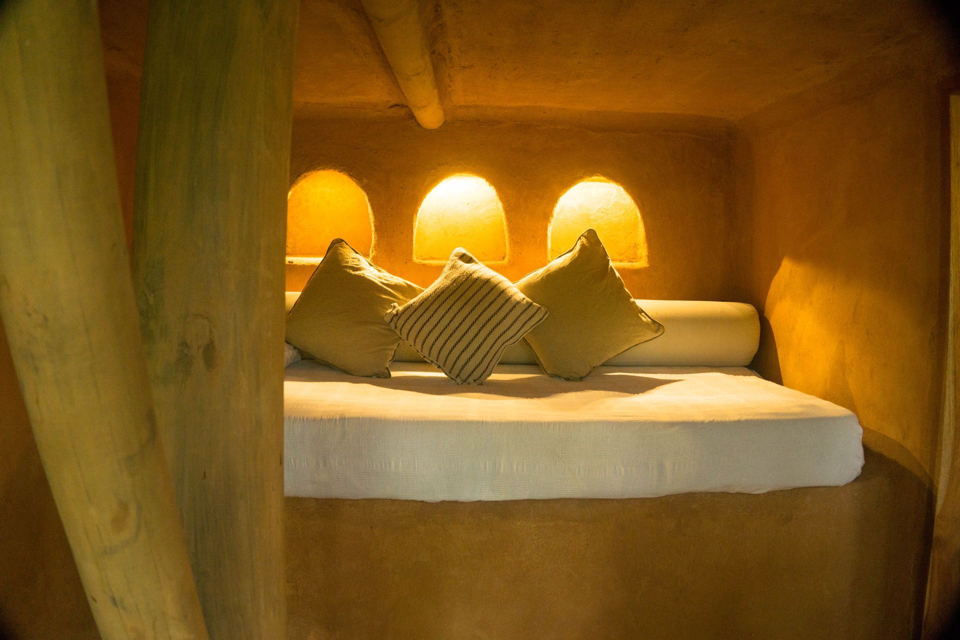 A bed with pillows on it is sitting in a corner of a room.