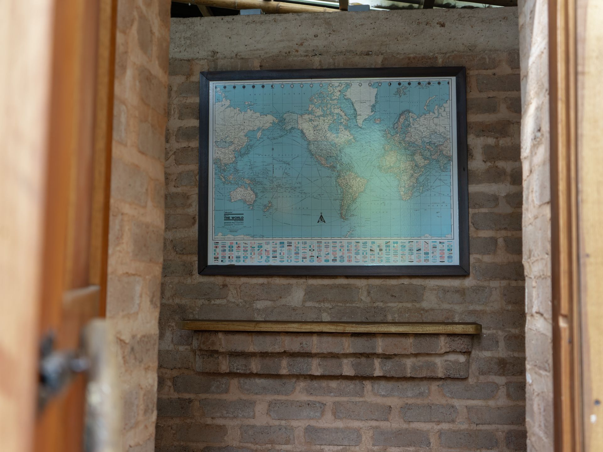 A map of the world is hanging on a brick wall