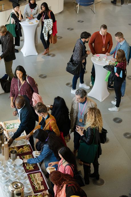 People mingling around a buffet table in a bright indoor event space