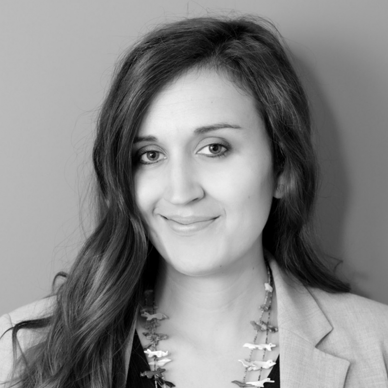 Smiling woman in a light blazer, photographed in black and white against a plain background