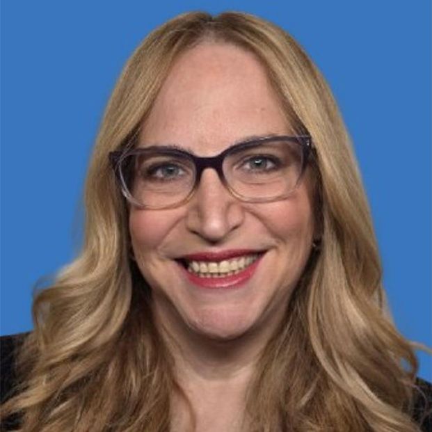 Smiling woman with blonde hair and glasses against a blue background