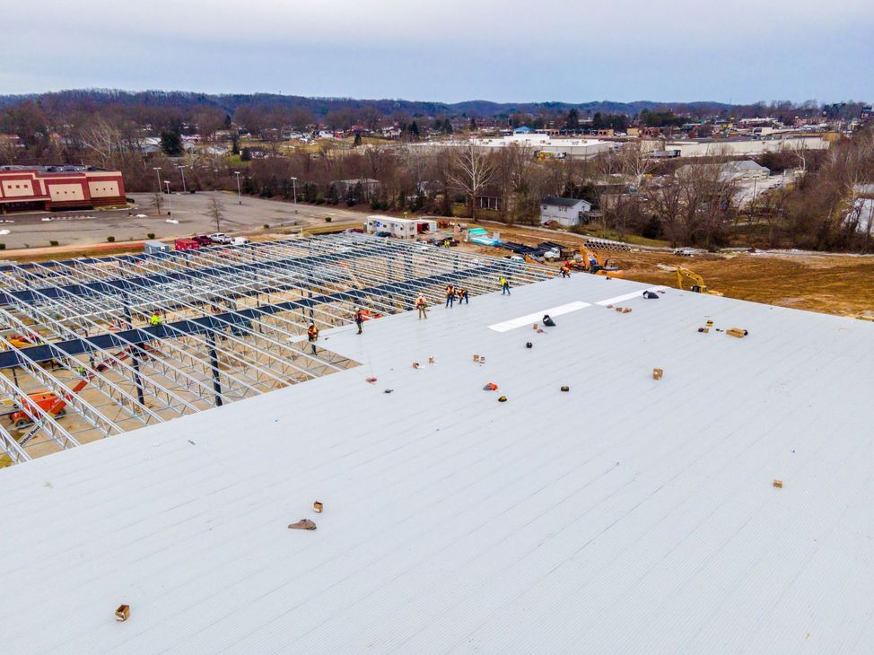 Snow-covered rooftop under construction with exposed framework and a winter landscape in the background