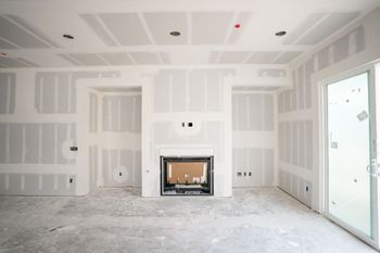Unfinished white living room with drywall, a fireplace, and a sliding glass door to the right.
