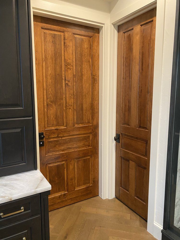 Two wooden doors, one open, in a room with a black cabinet and white trim.
