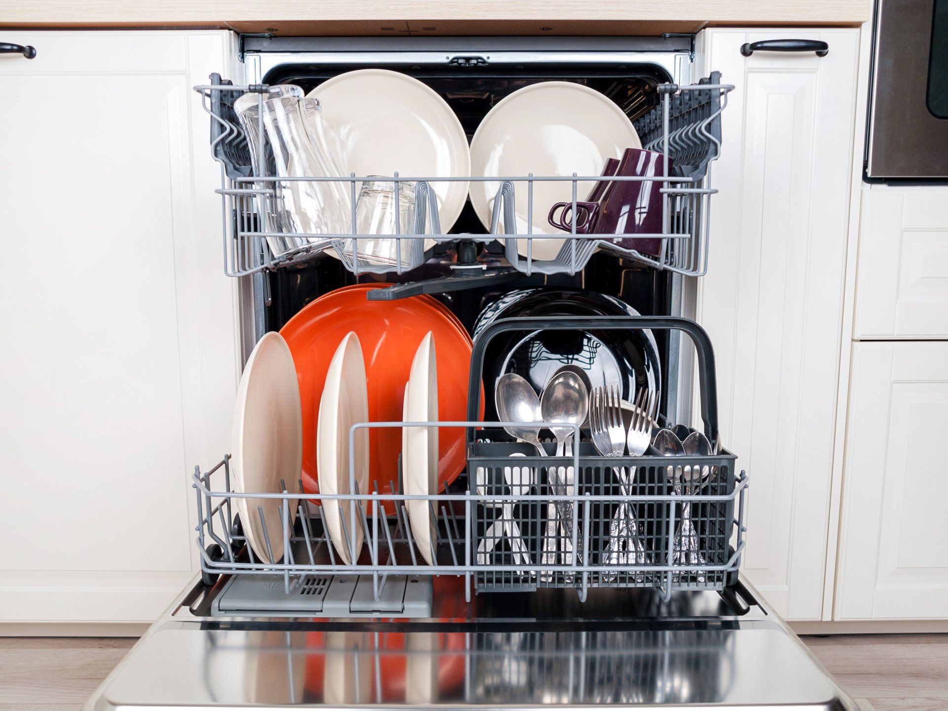 A dishwasher is filled with plates and silverware in a kitchen.