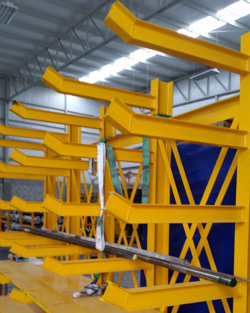 Vigas de acero industriales amarillas apiladas en un taller de fábrica.