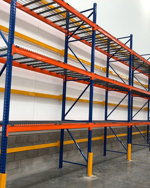 Estanterías industriales azules y naranjas en un almacén vacío.