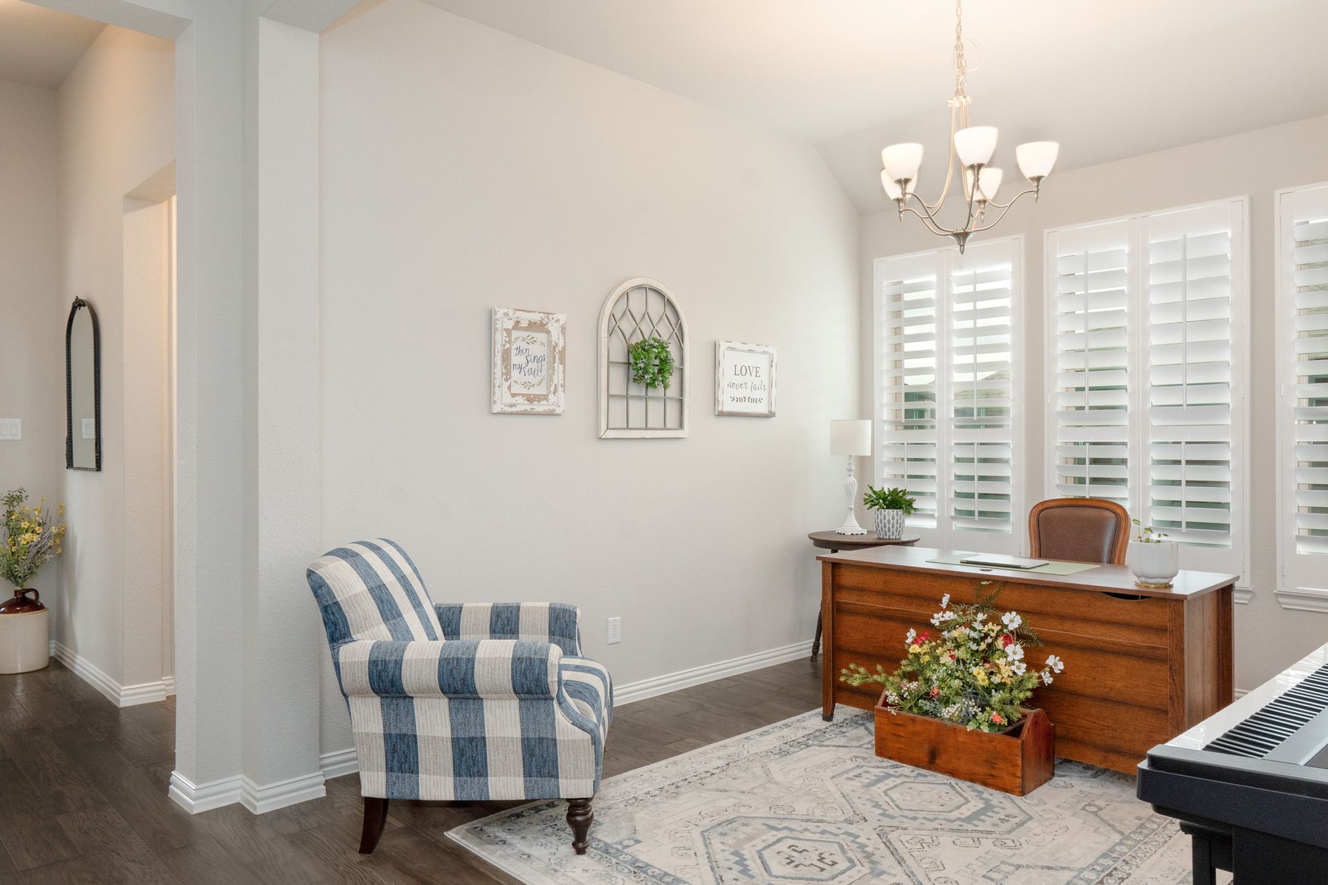 Bright living room with striped armchair, wooden sideboard, white shutters, and potted flowers on a rug.