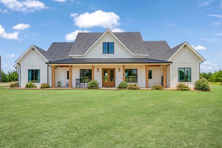 Large white suburban house with a gray roof and wide green lawn under a blue sky