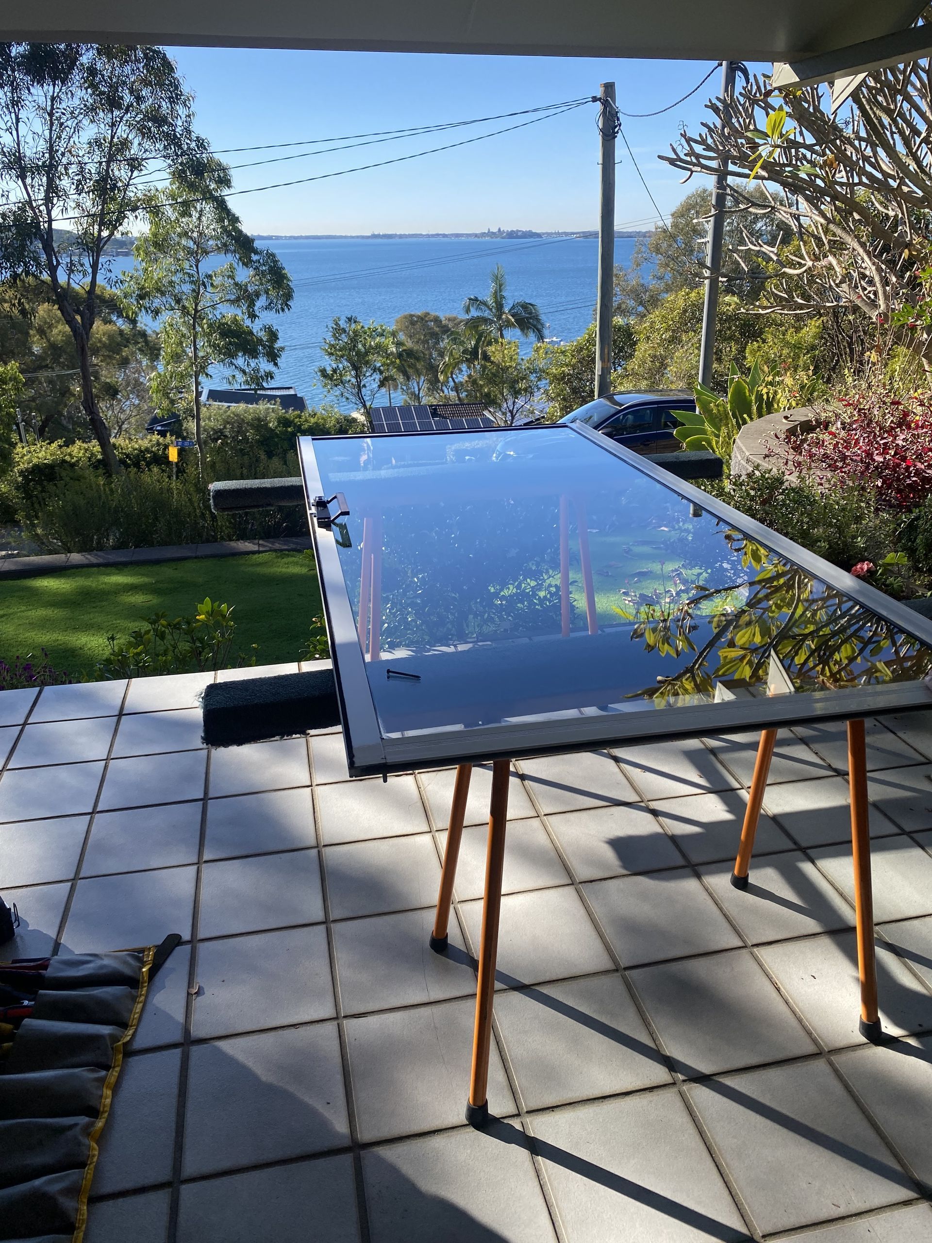 Large Glass Pane Resting On Orange Sawhorses Outdoors — Fix-A-Door in Wyong, NSW