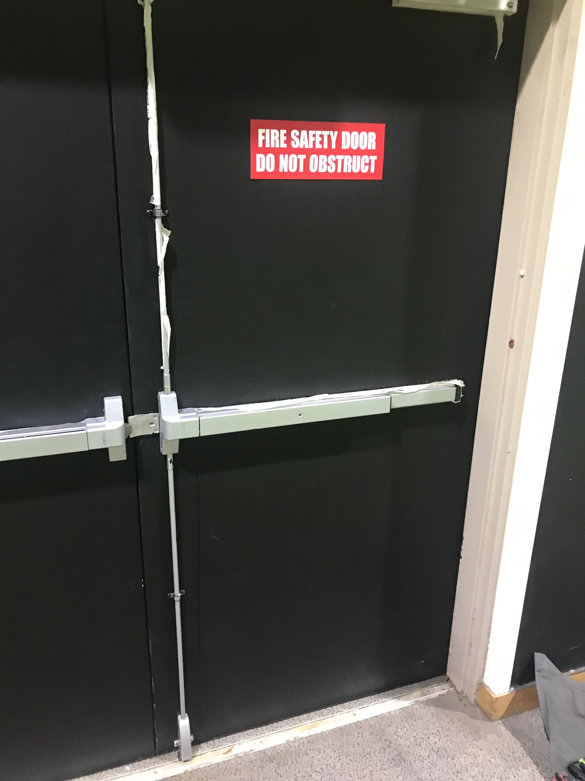 Black double doors with silver exit bars; red