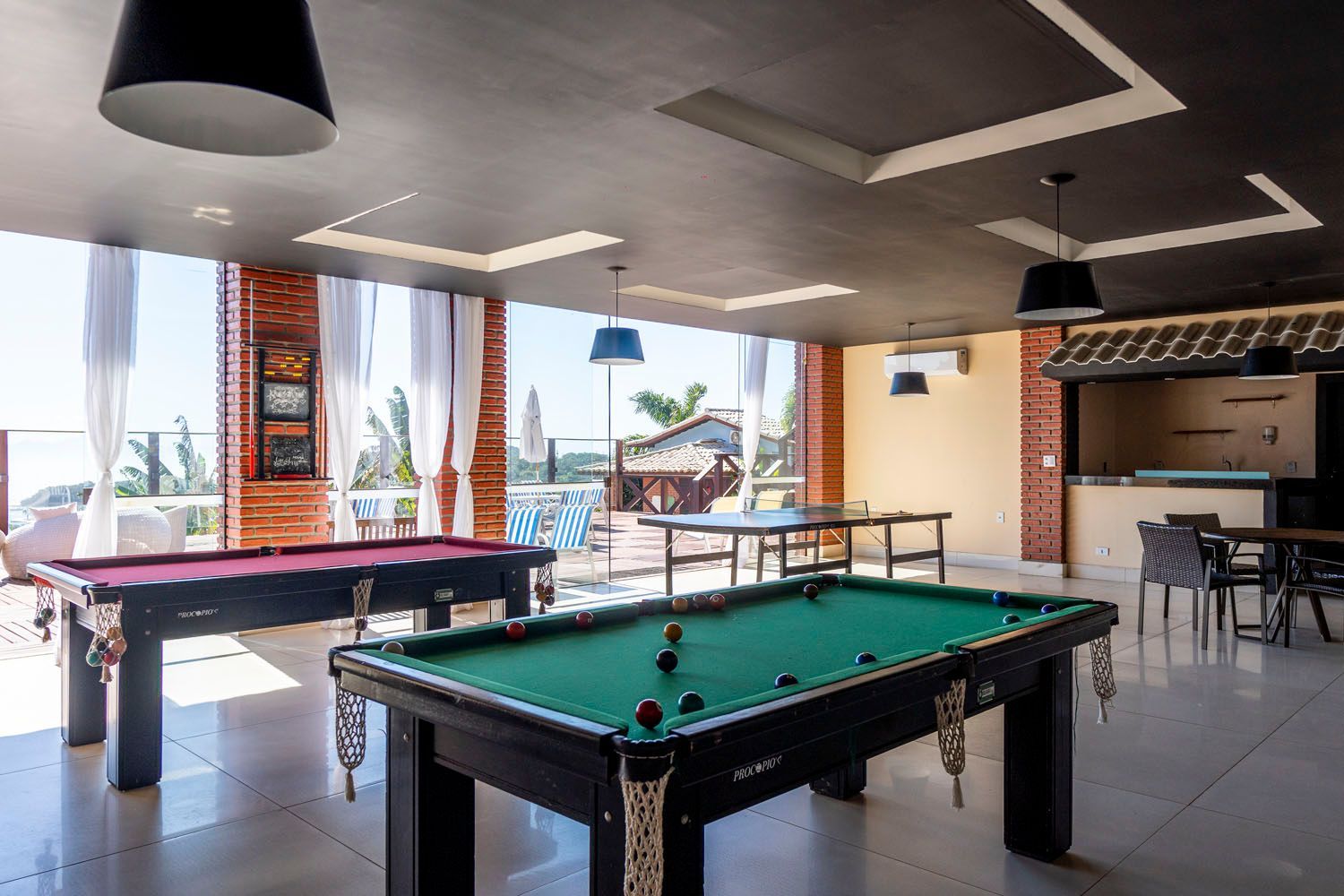 Uma mesa de sinuca e uma mesa de pingue-pongue em uma sala grande.