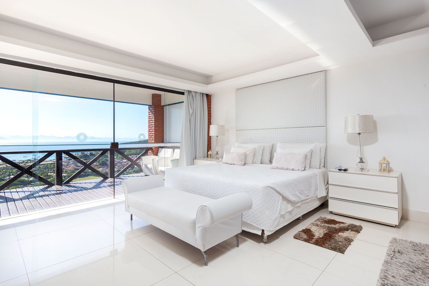 Um quarto com uma cama grande e uma varanda com vista para o oceano