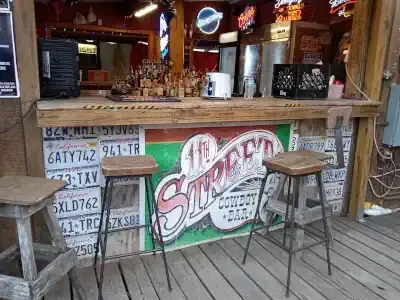 Outdoor bar counter with stools and a large “Sharkey’s” sign on the front