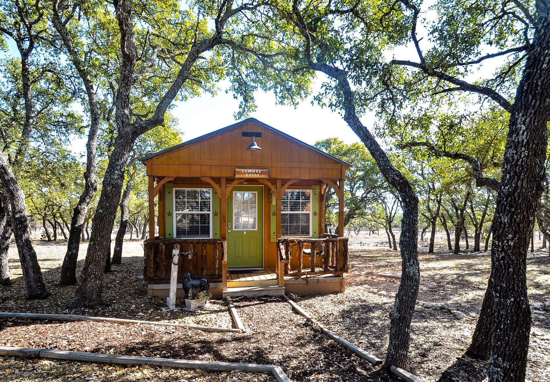 Small wooden cabin among trees in a wooded area, with a front porch and yellow door.