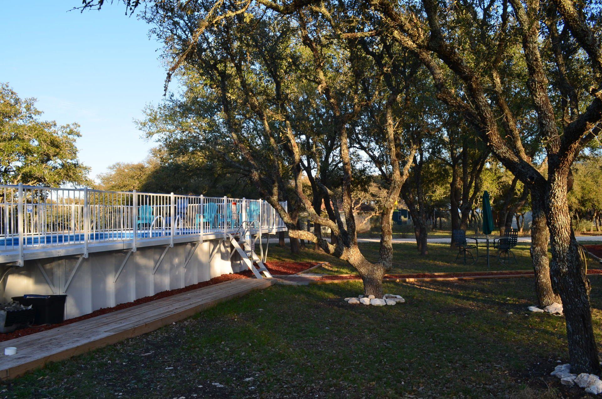 White pedestrian bridge in a sunlit park with trees and grass