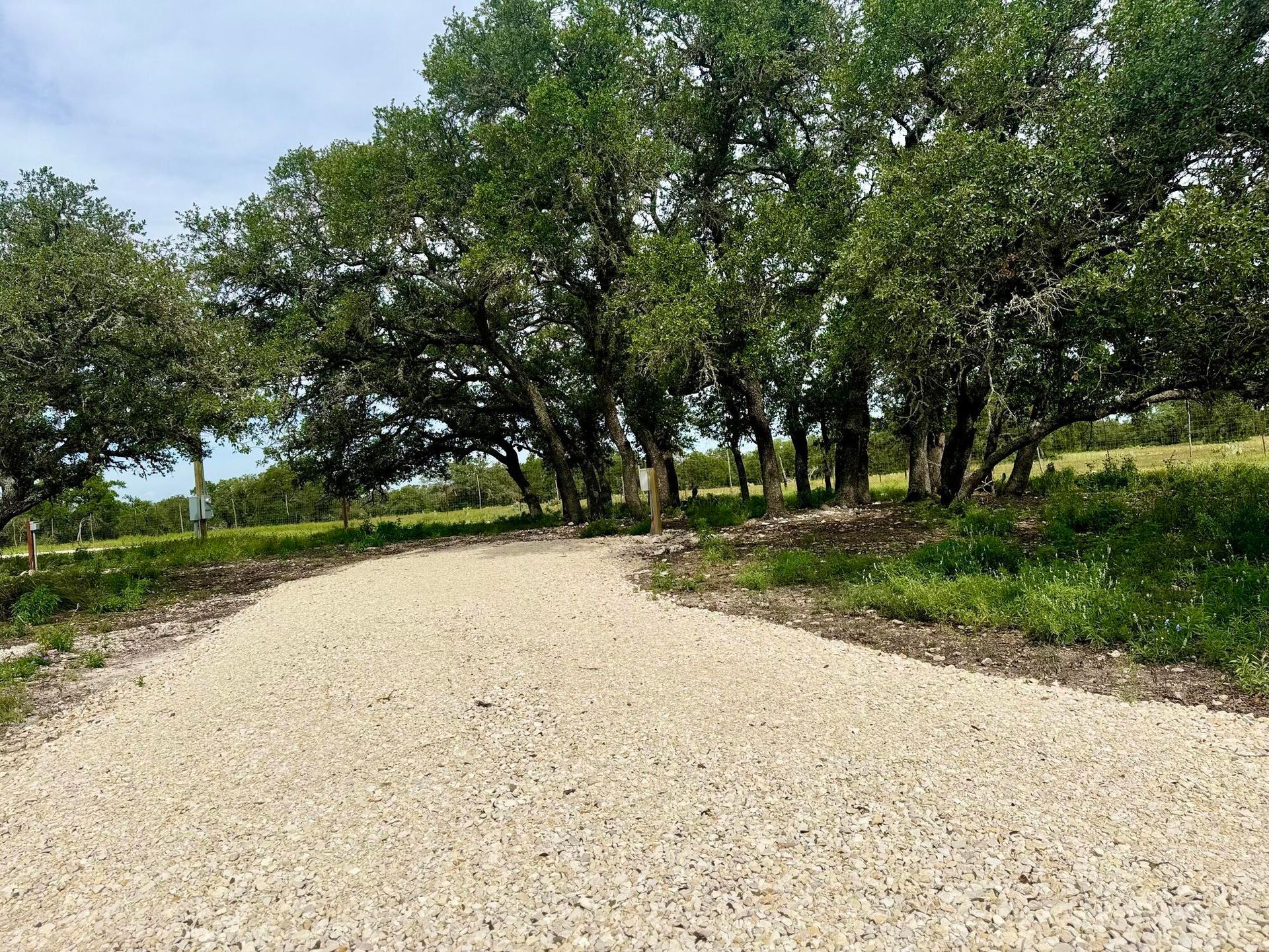 Curving gravel path through a green wooded park under a cloudy sky