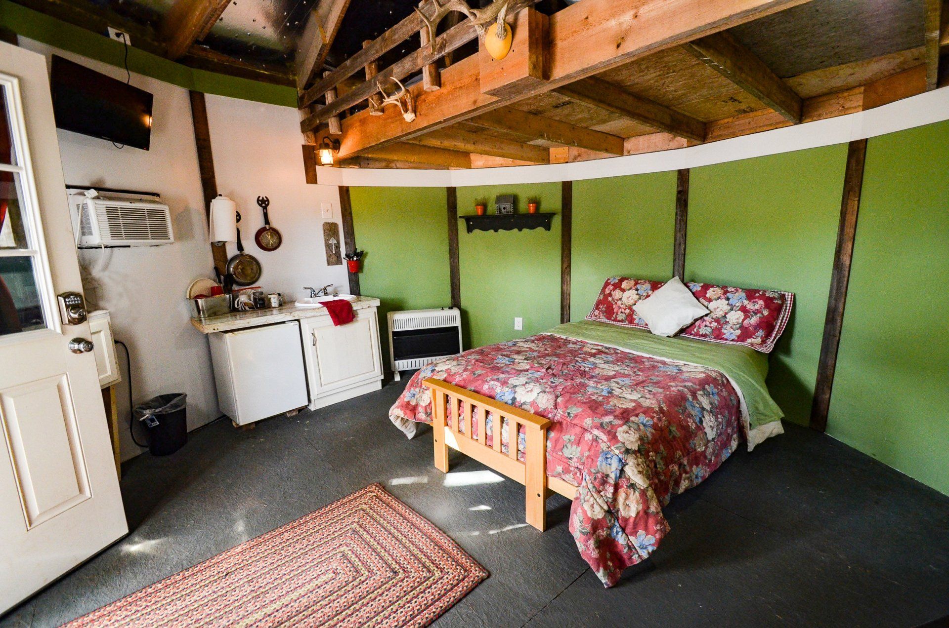 Cozy loft bedroom with a double bed, kitchenette, and exposed wooden beams