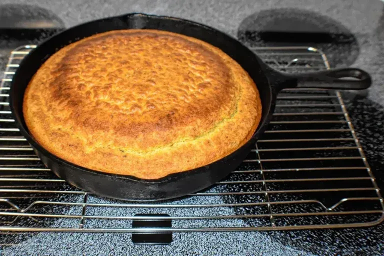 Golden baked cornbread in a cast-iron skillet on a wire rack on a countertop