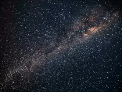 Starry night sky with the Milky Way stretching diagonally across a dark horizon